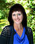 Professional headshot of a professor in a blue dress with lacy shawl. Blue eyes