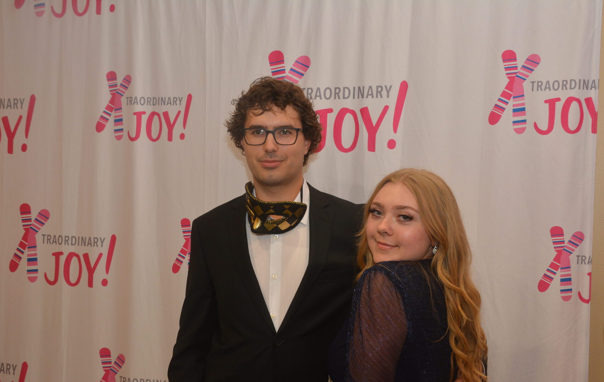 Couple posing in front of the Xtraordinary Joy backdrop at the event in Gainesville, Florida.