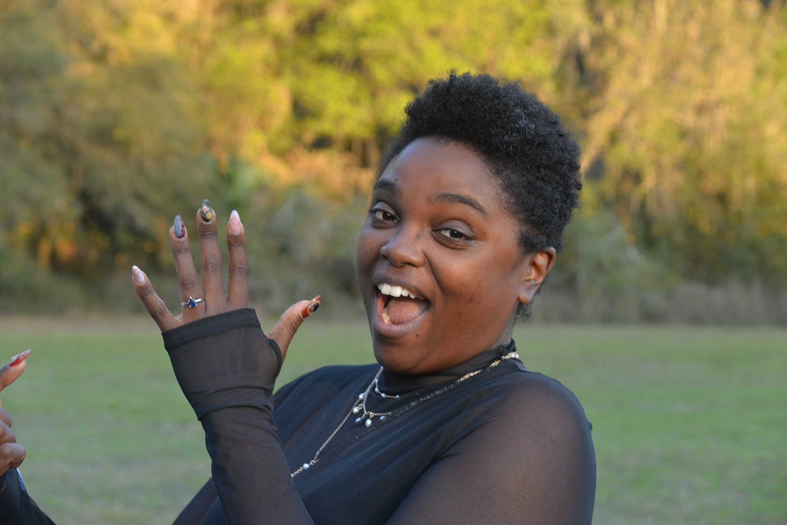 Newly engaged woman joyfully showing her engagement ring after an outdoor proposal in Gainesville, Florida.