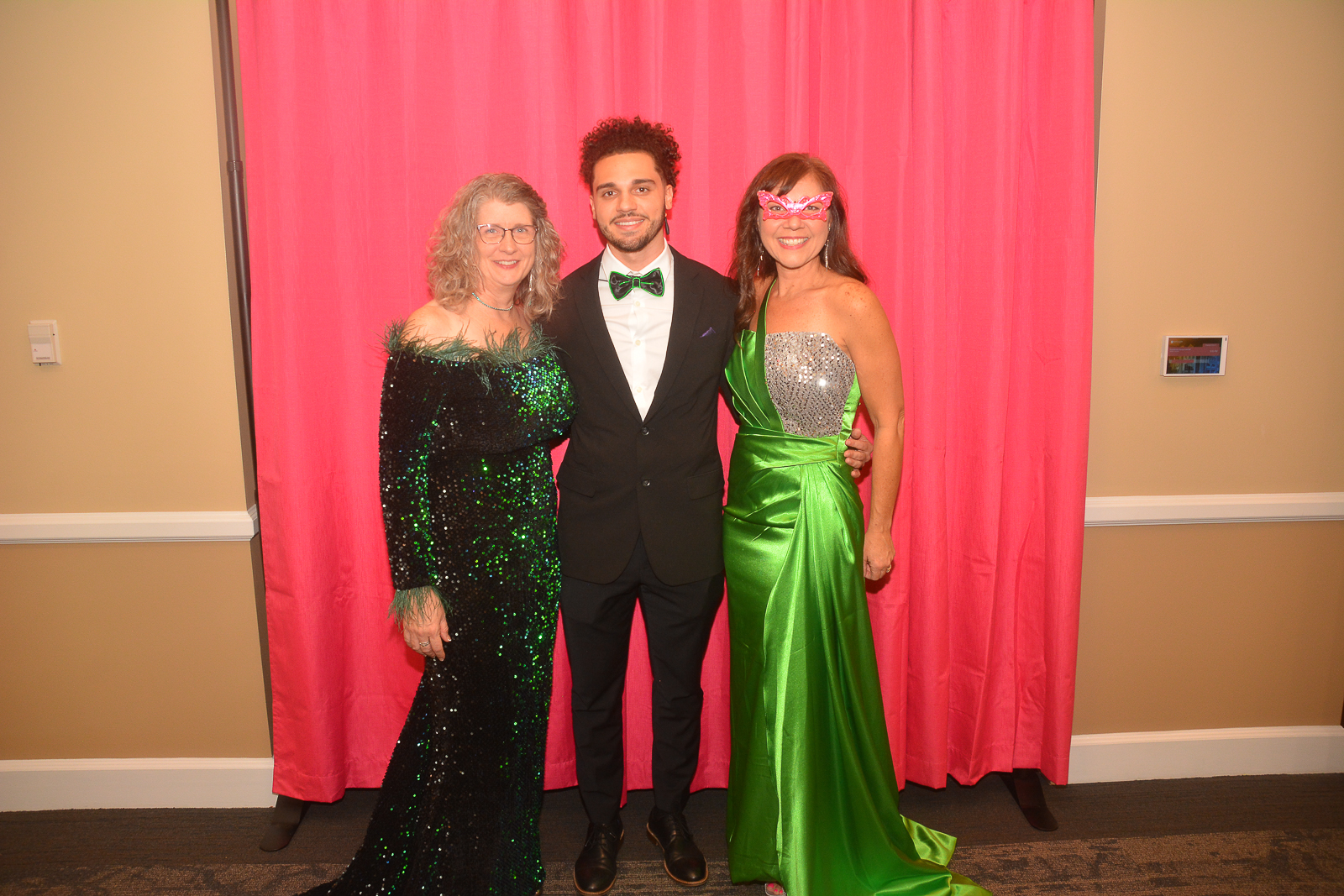 Three attendees posing in front of a pink backdrop at the Xtraordinary Joy event in Gainesville, Florida.